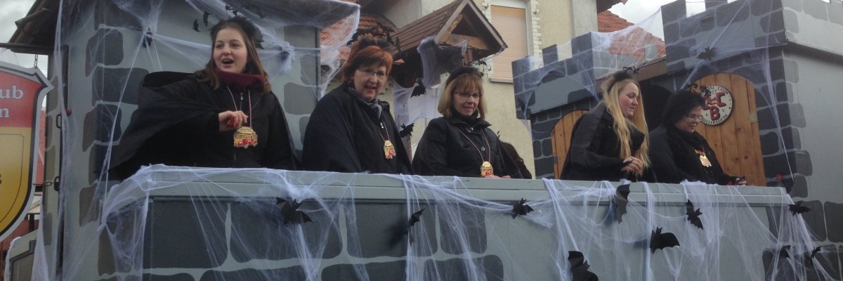 Faschingswagen dekoriert mit Burganlage, Spinnweben und Fledermäusen, darauf kostümierte Frauen des Carnevalclubs Bellersheim