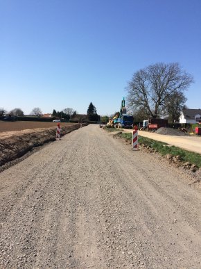 Baustraße geschotterte Baustraße mit Baufahrzeugen im Hintergrund