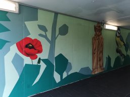 Graffiti der Schäferstatue, einer Holzstatue mit roten Blumen in der Bahnhofsunterführung