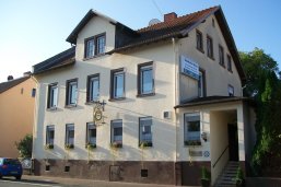 Gaststätte Deutsches Haus zweistöckiges Haus mit zwei Fensterreihen à 5 Fenstern, Dachgaube und Eingang in Anbau rechts, Blumenschmuck an allen Fenstern des Erdgeschosses