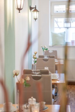 drei kleine gedeckte Tische mit Blumenschmuck und Stühlen im Café am Markt