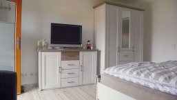 FeWo Schäferstube, heller Wohn-Schlafraum mit Schaf-und-Schäfer-Figuren auf Sideboard