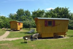 zwei Wagen der Schäferwagenherberge mit Korbstühlen davor