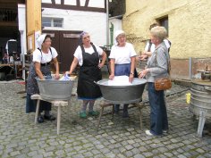 Waschtag im Heimatmuseum, Frauen in Arbeitskleidung und Kopftüchern an zwei Zinkwannen mit Waschbrett
