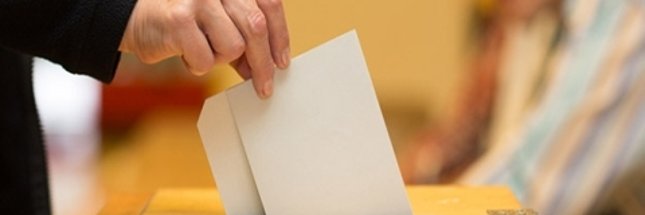 Hand wirft Wahlumschlag in Wahlurne