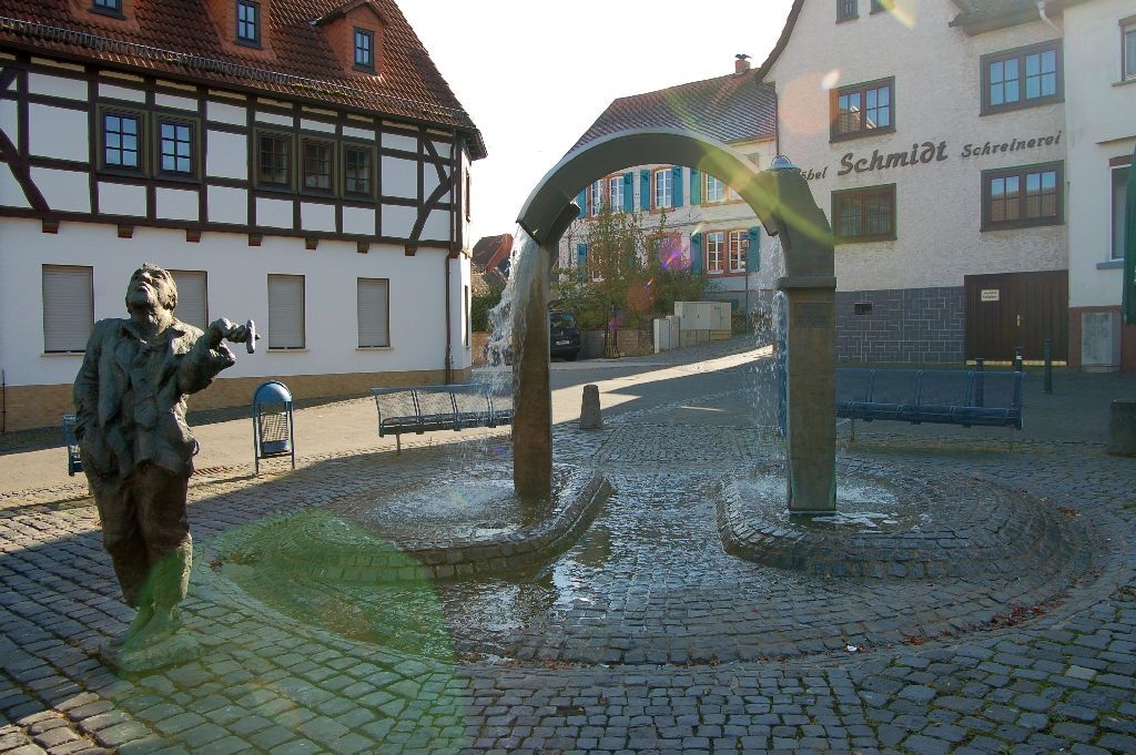 Hungen Marktplatzbrunnen mit Heiner-Statue, durch den Brunnebogen sieht man das Pfarrhaus