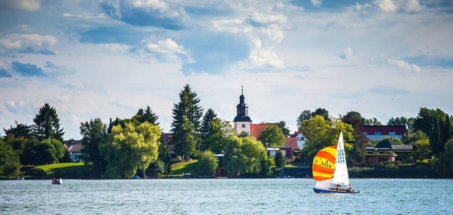 Inheidener / Trais Horloffer See mit Segelboot Segeler auf dem See, im Hintergrund Kirchturm Trais Horloff